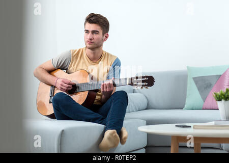 Hübscher junger Mann spielt akustische Gitarre Stockfoto