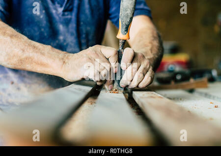 Zimmermann bei der Arbeit, Er schnitzt Holz mit einem Holzbearbeitung Werkzeug, Hände, Nahaufnahme, Zimmerei und Handwerkskunst Konzept Stockfoto