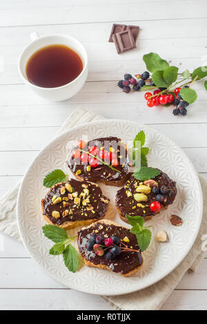 Sandwiches mit Schokoladencreme, Pistazien und frische Beeren auf einer Platte Stockfoto