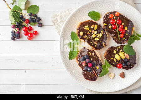 Sandwiches mit Schokoladencreme, Pistazien und frische Beeren auf einer Platte Stockfoto