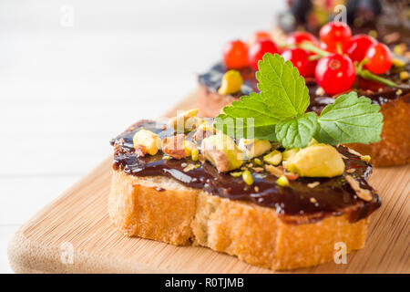 Sandwiches mit Schokoladencreme, Pistazien und frische Beeren auf Holz, das Board Stockfoto