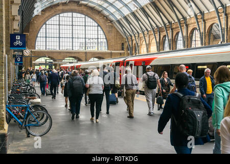 Pendler hinter einen Zug bei einer Plattform in King's Cross Station an einem sonnigen Tag Sommer, London, UK Stockfoto