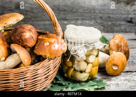 Marinierte Pilze Steinpilze in rustikalem Glas auf Holztisch, gebeizt, hausgemachte Marmeladen vorbereiten im Herbst Stockfoto