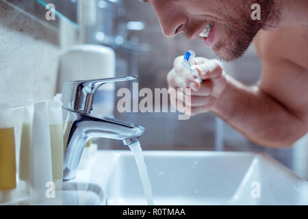 Die Jungen gut aussehenden bärtigen Mann seine Zähne putzen, bevor Sie zu Bett gehen