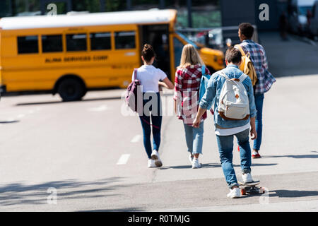 Ansicht der Rückseite des Gruppe von jugendlich Gelehrten walking Bus zur Schule durch Parken Stockfoto