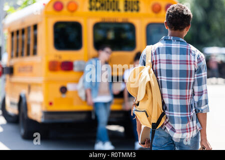 Ansicht der Rückseite des jugendlich Schüler zu Fuß zu Klassenkameraden lehnte sich auf School Bus Stockfoto