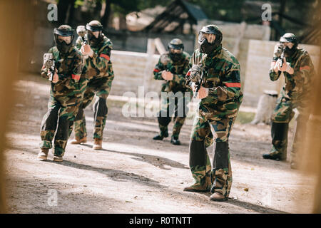 Paintball Team in Uniform und Schutzmasken spielen paintball mit Marker Gewehren im Freien Stockfoto