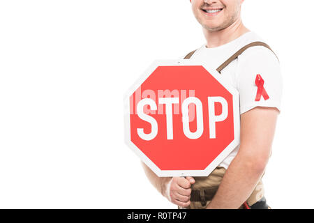 7/8 Schuß von lächelnden Builder mit aids awareness red ribbon auf die Holding Stop Schild isoliert auf weißem Stockfoto