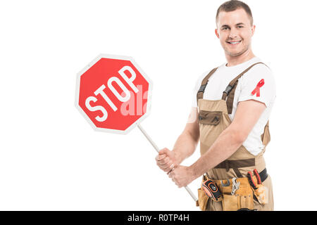 Glücklich nach Builder mit aids awareness red ribbon auf die Holding Stop Schild und Kamera isoliert auf weißem Stockfoto