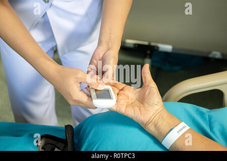 Krankenschwester Kontrolle der Blutzuckerspiegel patoent mit glucometer im Krankenhaus Stockfoto