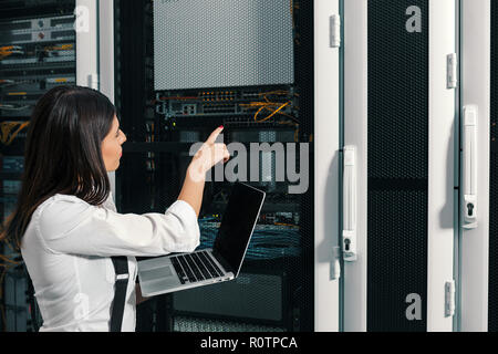 Techniker apecialist Frau mit Laptop, während Server Analyse im Server Raum Stockfoto