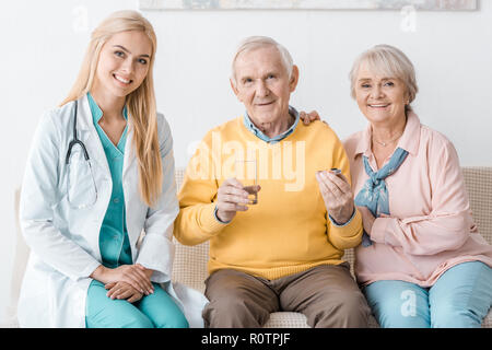 Junge weibliche Arzt, der Medizin zu den älteren Patienten Stockfoto