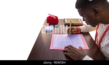 Ein afrikanisches Geschäft Mann in seinem Büro Tabelle arbeiten und Schreiben auf ein Dokument mit jotter, Stift, Tablet auf den Tisch mit einem weißen Hintergrund. Hand und h Stockfoto