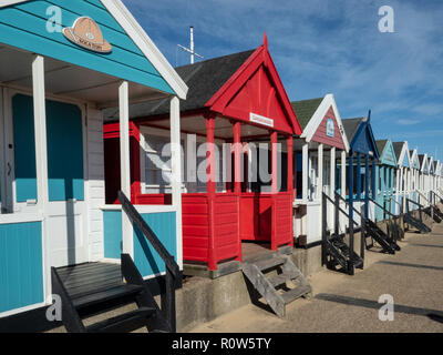 Eine Reihe von bunten Badekabinen entlang der Küste von Southwold gegen einen strahlend blauen Himmel Stockfoto