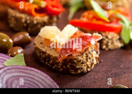 Nahaufnahme von verschiedenen mini Sandwiches auf einem Schneidebrett und Holztisch. Stockfoto