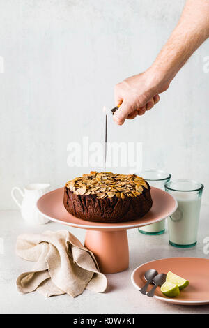 Glutenfreie und vegane Schokolade Mandel paleo Kuchen auf den Tisch und die Hand eines Mannes Beleuchtung eine festliche Sparkler Stockfoto