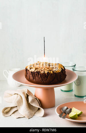 Glutenfreie und vegane Schokolade Mandel paleo Kuchen auf dem Tisch mit brennenden festliche Sparkler Stockfoto