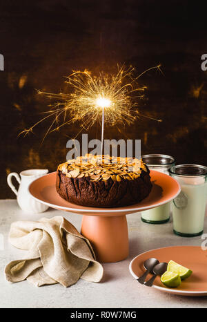 Glutenfreie und vegane Schokolade Mandel paleo Kuchen auf dem Tisch mit brennenden festliche Sparkler Stockfoto