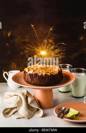Glutenfreie und vegane Schokolade Mandel paleo Kuchen auf dem Tisch mit brennenden festliche Sparkler Stockfoto
