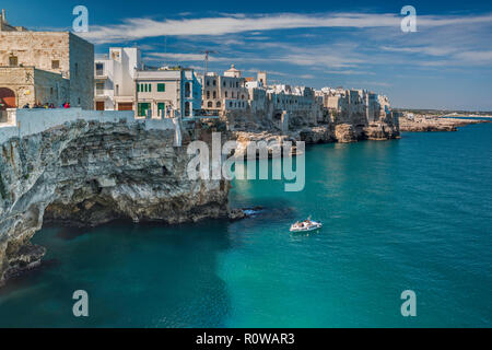 Häuser thront auf Felsen über Adria, Boot nähern Höhle, vom Largo Ardito Viewpoint, in Polignano a Mare, Apulien, Italien Stockfoto