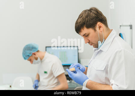 Arzt Mikroskop. Zahnarzt ist die Behandlung von Patienten in der modernen zahnmedizinischen Büro. Die Bedienung erfolgt mittels Fangdamms durchgeführt. Client wird eingefügt und restauriert, Zähne, Zahnersatz. Stockfoto