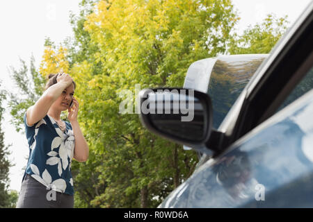 Frau Gespräch am Handy während Autopanne Stockfoto