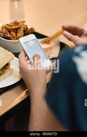 Frau in Essen bei der Verwendung von Mobile Telefon im Restaurant Stockfoto