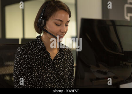 Customer Service Executive im Gespräch über das Headset am Schreibtisch Stockfoto