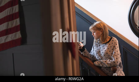 Frau mit Handy in Treppen zu Hause Stockfoto