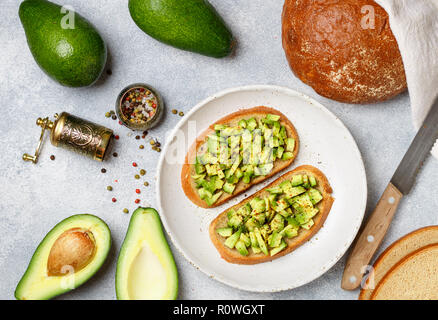 Scheiben Roggenbrot mit Avocado und Gewürze bunte Paprika und großen Meersalz, schwarzer Sesam. Guacamole. Sandwiches und Zutaten auf den Tisch. Se Stockfoto