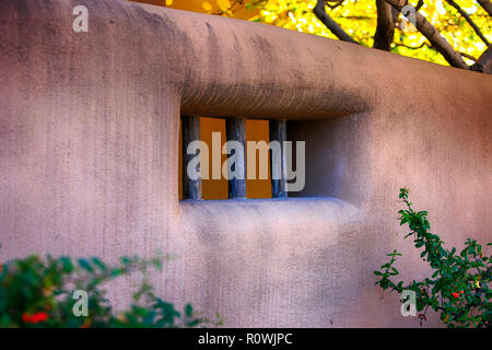 Adobe Wand mit Baumstamm Stil Fenster Design von Herbst farbige Bäume in Santa Fe, NM, USA umgeben Stockfoto