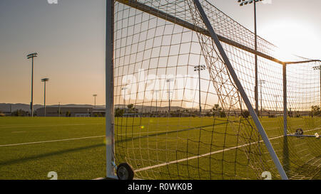 Leere Fußballplatz mit Torpfosten gegen Sonnenuntergang, Stadion Lichter in Sicht Stockfoto