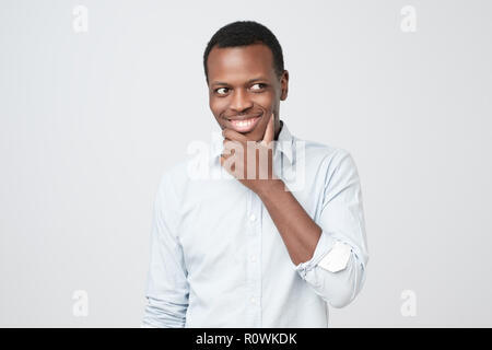 Sly , afrikanischer Mann Kinn Berühren mit dem Finger und Wegsehen. Stockfoto