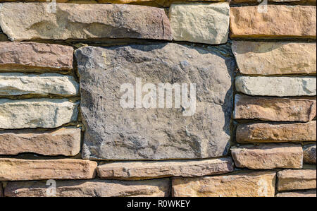 Stein Wand mit großen Stein für Kulisse. Ausgezeichnete rustikale Hintergrund Szene mit Platz für Text. Schöne rustikale bunte Textur. Stockfoto