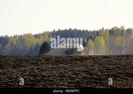 Salo, Finnland - 11. Mai 2018: Bauer Ausbringung von Gülle auf gepflügten Feld mit Traktor und Spreuverteiler auf einem wunderschönen Frühlingsabend im Süden Finnlands. Stockfoto