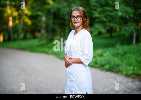 Ein junges Mädchen, die ein Arzt außerhalb steht, sind die Hände auf den Magen verbunden. Stockfoto