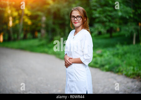 Ein junges Mädchen, die ein Arzt außerhalb steht, sind die Hände auf den Magen verbunden. Stockfoto