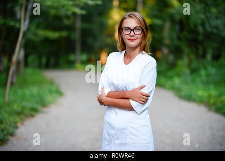 Ein junges Mädchen, die ein Arzt außerhalb steht, sind die Hände auf den Magen gekreuzt. Stockfoto