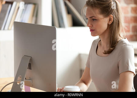 Ernsthafte weibliche Mitarbeiter beschäftigt, Arbeiten am Computer im Büro Stockfoto