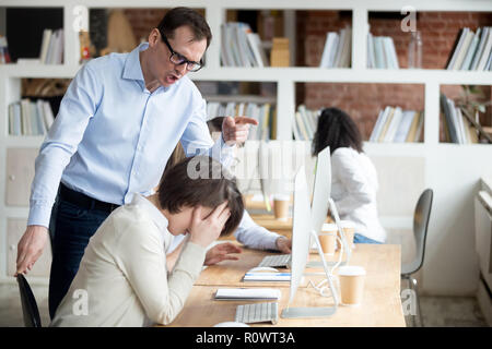 Wütend männliche Mitarbeiter Schrei an Arbeitnehmer die Schuld für Fehler Stockfoto