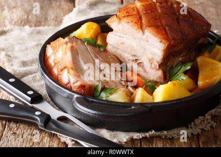 Lecker knusprig gebackenem Schweinefleisch in Bier mit Gemüse und Soße close-up in einer Pfanne auf dem Tisch. Horizontale Stockfoto