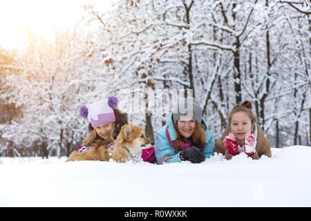 Happy Family - lächelnde Mutter und Töchter mit kleinen niedlichen Corgi flauschigen Welpen im Winter Tag Stockfoto