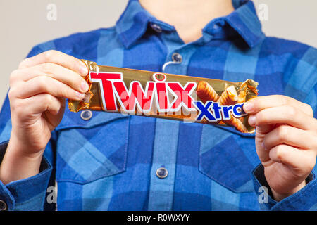 Vilnius, Litauen - 03. November 2018: Junge Hände halten twix Schokoriegel. Twix ist ein Schokoriegel von Mars, Inc., Bestehend aus Biskuit mit Karamel und Milchschokolade angewendet Stockfoto