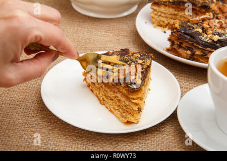 Weibliche Hand, die eine Gabel und hausgemachte Schokolade Kuchen liegen auf Weiß Untertasse zu probieren Stockfoto