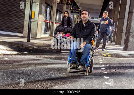 Behinderte Menschen in motorisierten Rollstuhl Crossing Road in London, UK. Stockfoto