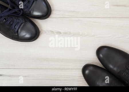Zwei Paare von schwarzem Leder Herrenschuhe auf grau Holz- Hintergrund mit Kopie Raum im Zentrum. Herren Accessoires. Ansicht von oben Stockfoto