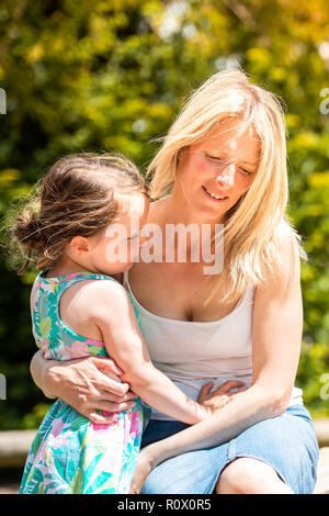 Ein hübsches, sportlich Mutter in Ihrem 40 Knuddel spielen mit ihrer Tochter im Park, das Spielen mit Sand Burgen Trentham Gardens, Stoke-on-Trent Stockfoto