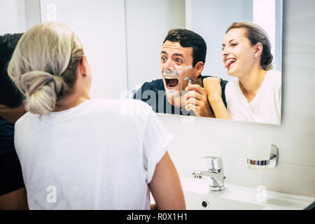 Glücklich und freundlich Paar zu Hause haben Spaß und lachen viel, während der Mann den Bart mit Schaum. - Liebe und Partnerschaft indoor Lebensstil für Jahrtausende Stockfoto
