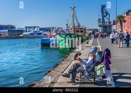 Ein älteres Ehepaar genießen Sie eine anothers Unternehmen, wie sie Fisch am Kai gegenüber Sunseeker Wharf am Hafen von Poole in Dorset. Stockfoto