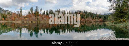 Herbst Farbe Wald und Blattwerk Landschaft umgeben einen idyllischen Bergsee in den Alpen der Schweiz, an einem späten Herbsttag mit Reflexionen im ... Stockfoto